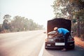 Serious african man using smartphone and holding his head by hands standing near his old broken car  with raised hood on the Royalty Free Stock Photo