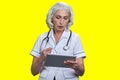 Serious aged gray-haired female doctor using tablet pc. Royalty Free Stock Photo