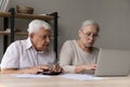 Serious aged spouses sit at desk manage household finances
