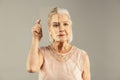 Serious aged woman holding a mirror near her face