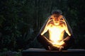 A serious, angry man sits in the dark outside with a bright light lamp on his lap. Pain, depression, stress or hatred concept