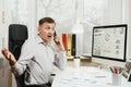 Serious and engrossed business man in shirt sitting at the desk, working at computer with modern monitor. Manager or worker.