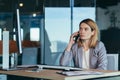 Serious and anxious business woman talking on the phone, working in a modern office at the computer, close-up photo