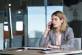 Serious and anxious business woman talking on the phone, working in a modern office at the computer, close-up photo