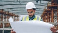 Serious Arab guy engineer checking construction plan and looking around outdoors Royalty Free Stock Photo