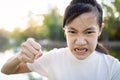 Serious asian child girl with her fist raised for threat warning or quarreling,angry female threatening with fist,about to punch,