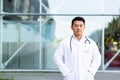 Serious asian doctor with folded arms on background of modern clinic outdoors Royalty Free Stock Photo