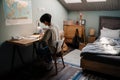 Serious asian guy studying with book while sitting at desk at home Royalty Free Stock Photo