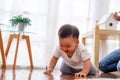 Serious Asian little boy crawling on floor while young father sitting next to him in living room Royalty Free Stock Photo