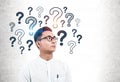 Serious Asian man in glasses, question marks Royalty Free Stock Photo