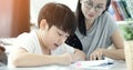 Asian mother with son doing homework in living room. Royalty Free Stock Photo