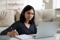 Serious Asian woman wearing headphones looking at laptop screen Royalty Free Stock Photo