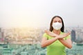 Serious Asian woman wearing a protection mask with making X sign with her arms to stop PM 2.5 air pollution in Bangkok city. Royalty Free Stock Photo