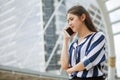 Serious asian young business woman talking on mobile phone in urban city .