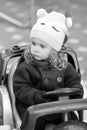 Serious and attentive baby girl driver observing traffic regulations. Black and white candid portrait of a child in the park