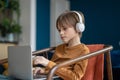 Serious attentive teen boy in headphones having educational online class on laptop.