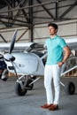 Serious attractive young man standing in front of small aircraft