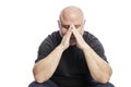 A serious bald middle-aged man in a black T-shirt is sitting with his hand in his face. Isolated over white background Royalty Free Stock Photo