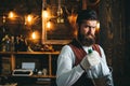 Serious barman. Restaurant staff. Bearded hipster wear waistcoat. Pub retro vintage interior. Barman with beard. Hipster