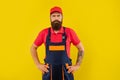 serious bearded deliveryman in work clothes on yellow background