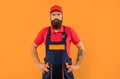 serious bearded deliveryman in work clothes on yellow background