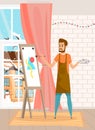 Serious bearded man drawing the picture holding paint brush standing near easel in home interior