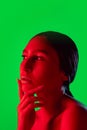 Beautiful east woman close up portrait isolated on green background in red neon light Royalty Free Stock Photo