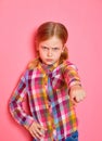 Serious beautiful little girl pointing a finger at you on pink background. Royalty Free Stock Photo