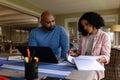 Serious biracial parents using laptop, looking at bills sitting at table with daughter in background Royalty Free Stock Photo