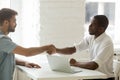 Serious black boss greeting Caucasian candidate with handshake