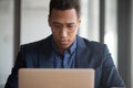 Serious black employee working on laptop consulting client