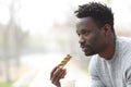 Serious black man with snack bar and coffee in a park Royalty Free Stock Photo