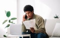 Serious black teen guy studying online from home, talking to his tutor about coursework paper on smartphone