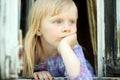 Serious blond little girl looking out the window Royalty Free Stock Photo
