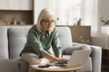 Serious blonde elderly woman in glasses doing domestic financial work Royalty Free Stock Photo