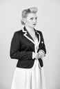 Serious blonde girl in jacket looks up. Woman in pin-up style dressed in jacket on grey Royalty Free Stock Photo