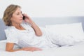 Serious blonde woman lying on bed making a phone call Royalty Free Stock Photo