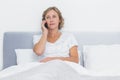 Serious blonde woman making phone call in bed Royalty Free Stock Photo