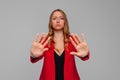 Serious blonde young woman keeping hands in stop gesture, trying to defend herself as if saying: Stay away from me. Stay home. Royalty Free Stock Photo