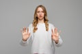 Serious blonde young woman keeping hands in stop gesture, trying to defend herself as if saying: Stay away from me, wears white Royalty Free Stock Photo