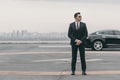 serious bodyguard standing with sunglasses and security earpiece on helipad and looking