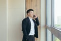 Serious boss asian businessman talking on the phone in a modern office center, makes a working call to colleagues Royalty Free Stock Photo