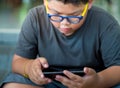 Asian boy have a serious face while playing game on smartphone Royalty Free Stock Photo