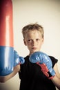 Serious boy strikes punching bag with blue gloves Royalty Free Stock Photo