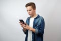 Serious boy using smartphone. Handsome teenage boy holding mobile phone