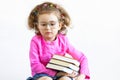 Serious, brooding, sad, distracted, cute smart little girl in funny big glasses reading a stack of paper books. Training, educatio