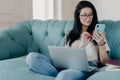Serious brunette female freelancer works remotely on laptop computer, sends text messages via smartphone connected to wireless Royalty Free Stock Photo