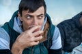 Serious brunette man drinking coffee or tea from disposable paper cup outdoors Royalty Free Stock Photo