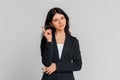 Serious brunette teen girl in black blazer pointing finger up, scolding or telling off someone, says: Attention please, standing Royalty Free Stock Photo