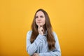 Serious brunette woman in denim blue shirt keeping finger on mouth, thinking Royalty Free Stock Photo